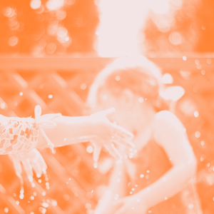 Image d'un enfant qui joue avec de l'eau dehors... en arrière plan, de la lumière.