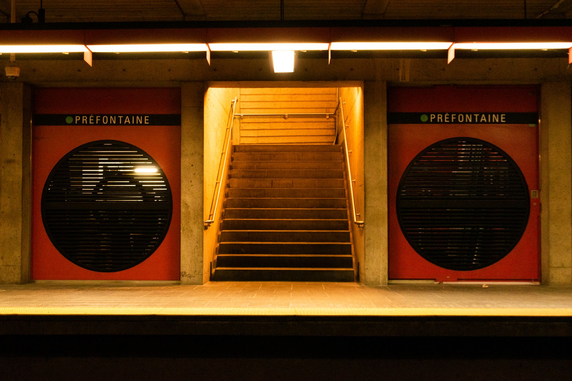Photo d'un escalier au métro Préfontaine. Avec deux cercles de chaque côté. Ça ressemble à un ancien joueur de cassette.